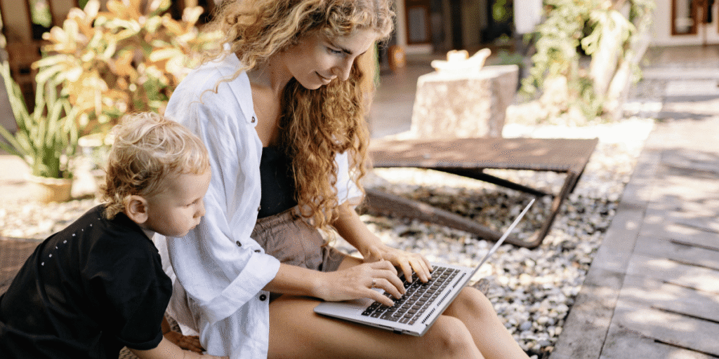 frau arbeitet am laptop während kind daneben sitzt
