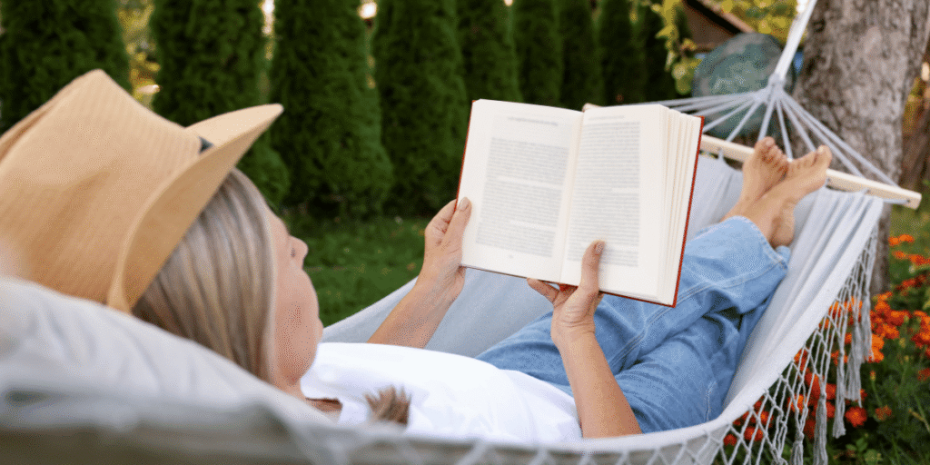 frau liegt in der hängematte und liest ein buch